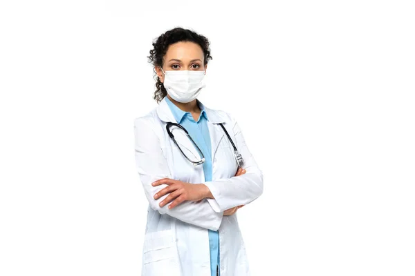 Medico afroamericano in maschera medica e cappotto bianco isolato su bianco — Foto stock