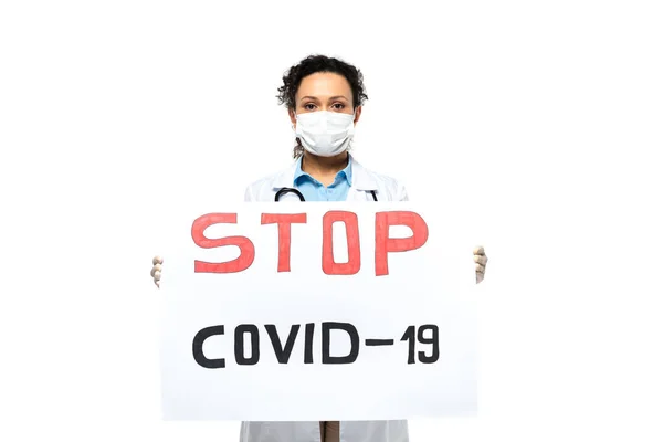 Африканский американский врач в защитной маске держит плакат с остановкой covid-2019 надписи изолированы на белом — стоковое фото