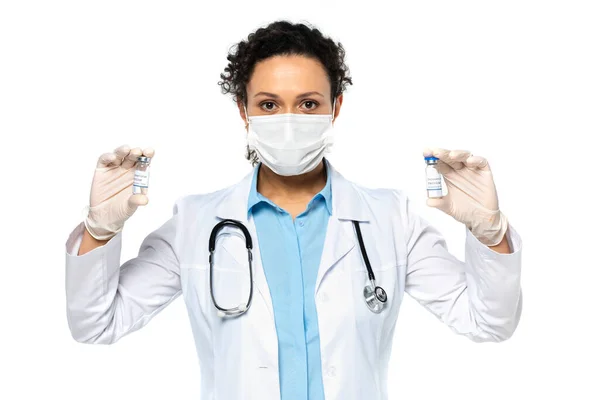 African american doctor in medical mask holding vaccine isolated on white — Stock Photo