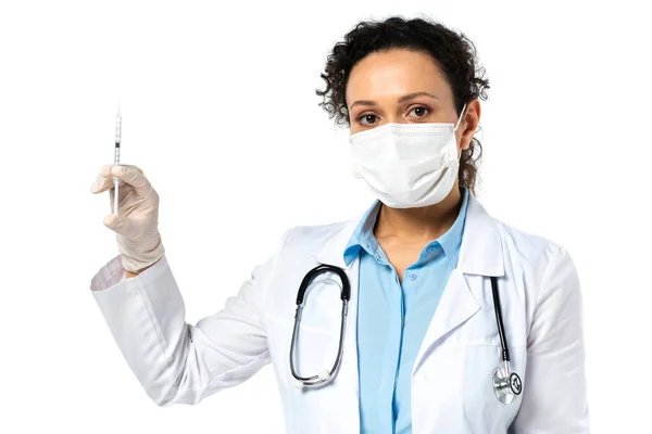 Médico afroamericano con máscara médica que sostiene jeringa con vacuna aislada en blanco - foto de stock