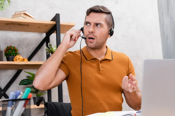 Hombre discapacitado en el gesto de auriculares mientras trabaja en casa - foto de stock