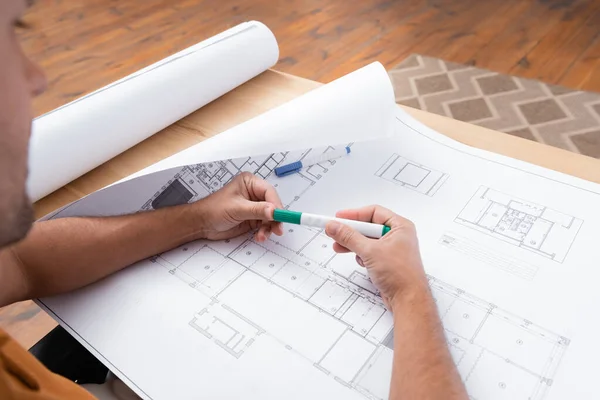 Cropped view engineer holding felt pen near blueprint while working at home, blurred foreground — Stock Photo