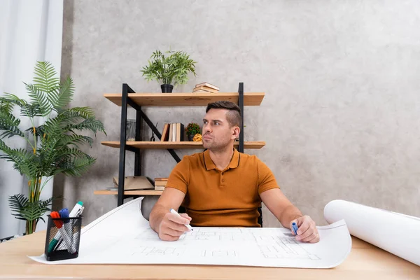 Young architect holding felt pen while thinking near blueprint at home — Stock Photo