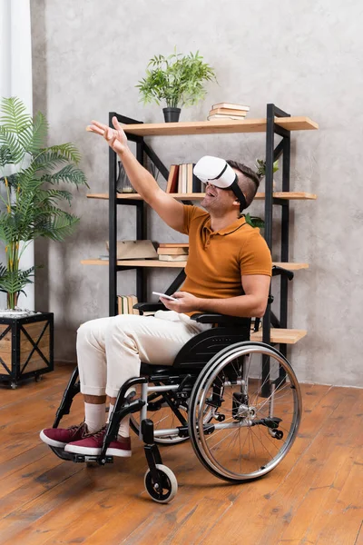 Amazed disabled man gesturing while gaming in vr headset at home — Stock Photo