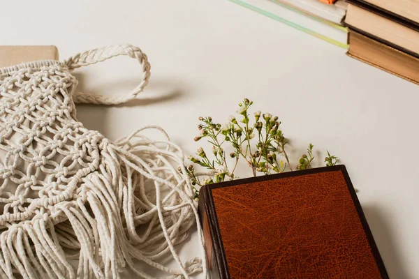 Fiori di campo in libro con copertina rigida vicino borsa a tracolla lavorata a maglia su bianco — Foto stock