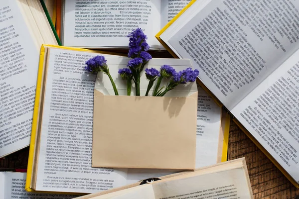 Vista superior de flores púrpuras en sobre sobre sobre pila de libros — Stock Photo