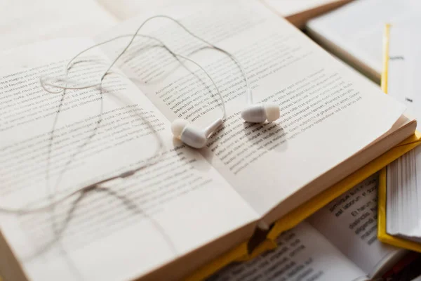 Fones de ouvido brancos na pilha de livros desfocados — Fotografia de Stock