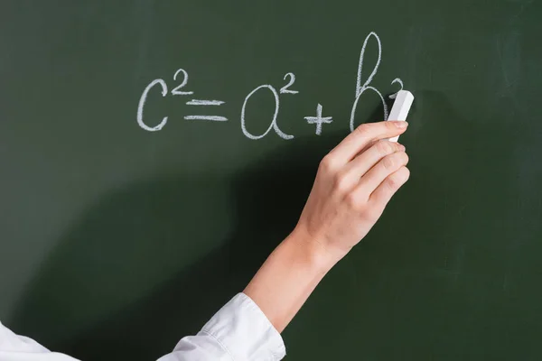 Cropped view of teacher writing equation on chalkboard — Stock Photo