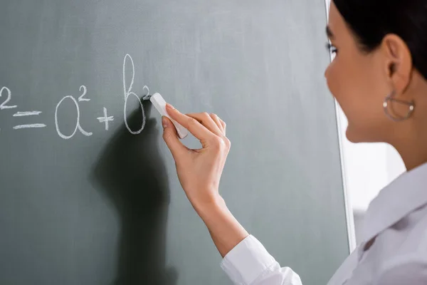 Sfocato insegnante scrittura formula matematica sulla lavagna — Foto stock