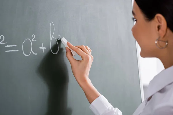 Blurred teacher writing mathematic formula on chalkboard — Stock Photo
