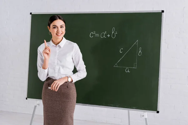 Positiver Lehrer zeigt mit Finger auf Matheunterricht in der Schule — Stockfoto