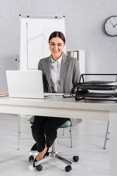 Femme d'affaires joyeuse regardant ordinateur portable sur la table de travail — Photo de stock