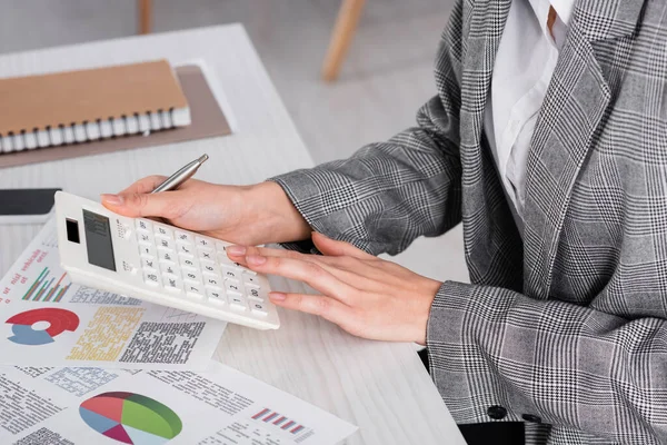 Ausgeschnittene Ansicht einer Geschäftsfrau mit Taschenrechner in der Nähe von Dokumenten auf dem Tisch — Stockfoto