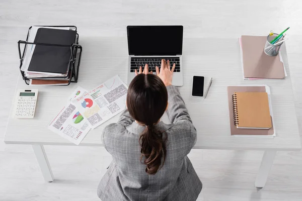 Vue aérienne de la femme d'affaires à l'aide d'un ordinateur portable avec écran vierge près des papiers et calculatrice — Photo de stock