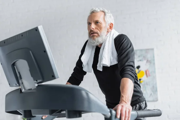 Bearded man with grey hair exercising on treadmill at home — Stock Photo