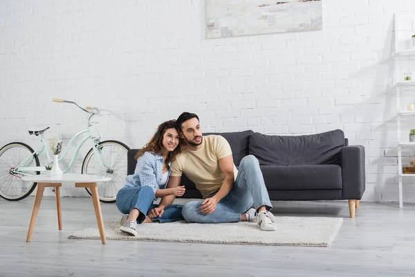 Glücklich interracial paar sitzen auf teppich im wohnzimmer — Stockfoto