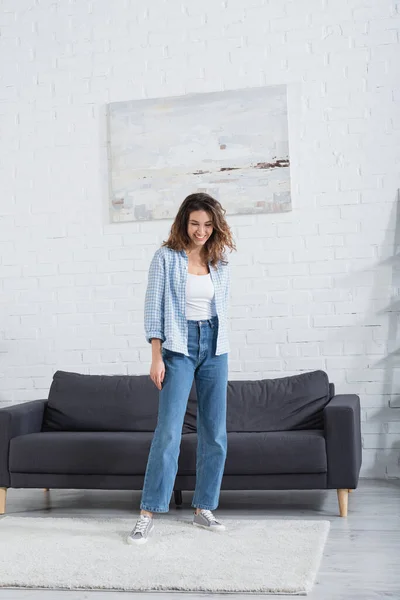 Pleine longueur de jeune femme heureuse souriant dans le salon moderne — Photo de stock