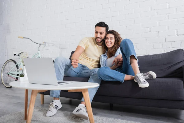 Happy muslim man watching movie on laptop with smiling girlfriend — Stock Photo