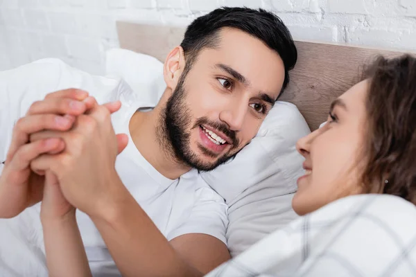 Barbuto uomo musulmano che si tiene per mano con fidanzata felice in primo piano offuscata — Foto stock