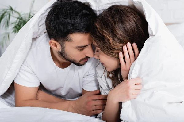 Interracial couple with closed eyes lying under blanket — Stock Photo