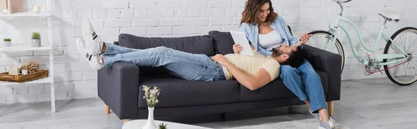 Muslim man resting on couch with digital tablet near happy girlfriend, banner — Stock Photo