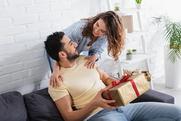Glücklicher muslimischer Mann hält verpacktes Geschenk neben lächelnder Freundin — Stockfoto