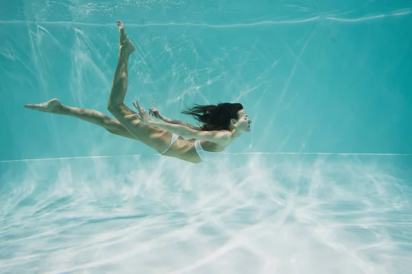 Brunetta donna in costume da bagno bianco immersioni in piscina — Foto stock