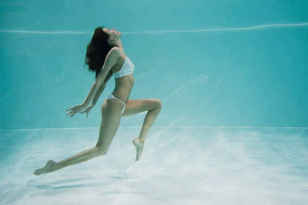 Mujer elegante en traje de baño nadando en la piscina - foto de stock