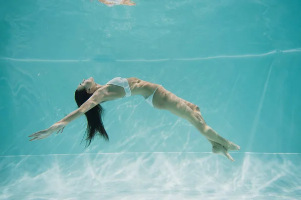 Peaceful young woman in white swimsuit swimming in pool — Stock Photo