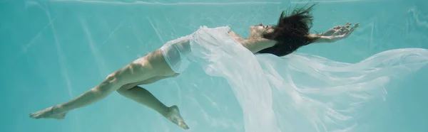 Грациозная молодая женщина в белом платье плавает в бассейне, баннер — стоковое фото