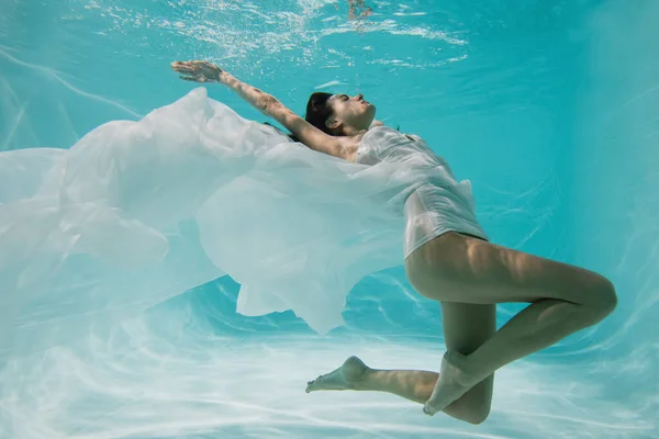 Donna graziosa in abito bianco immersioni in piscina — Foto stock