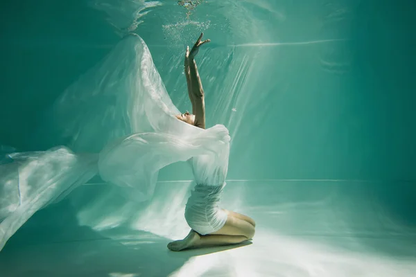 Молодая женщина в платье сидит в бассейне с голубой водой — стоковое фото