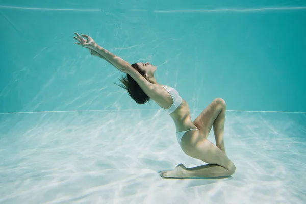 Elegante mujer joven en traje de baño nadando en la piscina - foto de stock