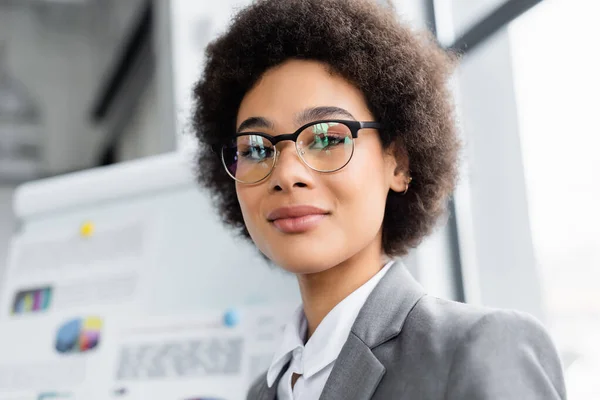 Mulher de negócios afro-americana em óculos olhando para a câmera no escritório — Fotografia de Stock
