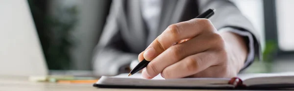 Cropped view of blurred businesswoman writing on notebook, banner — Stock Photo