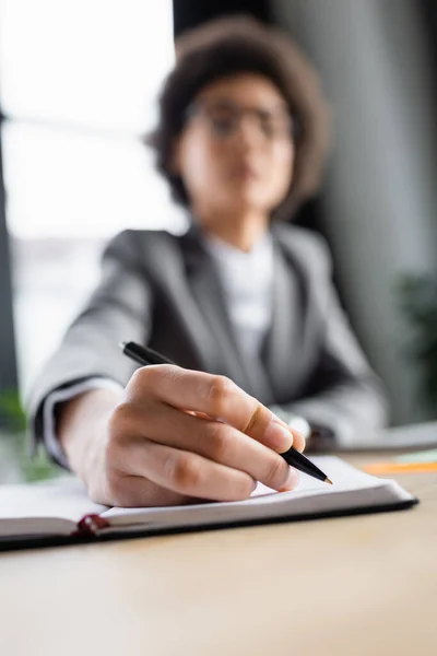 Verschwommene Geschäftsfrau schreibt an Kopierbuch im Büro — Stockfoto