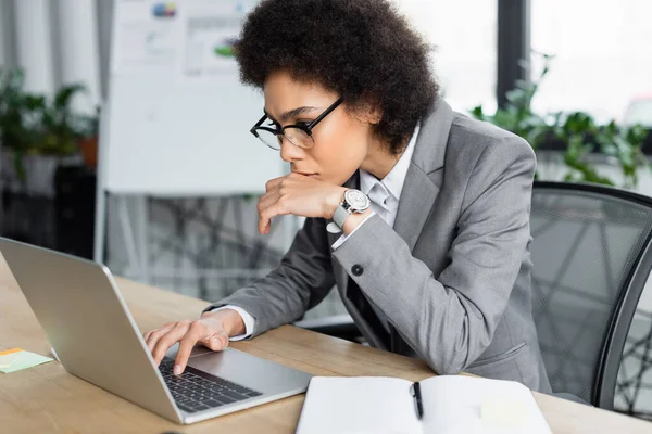 Gerente afroamericano mirando el ordenador portátil en la oficina - foto de stock