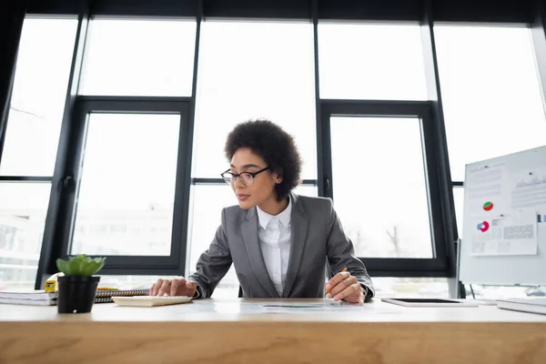 Afrikanisch-amerikanische Geschäftsfrau mit Taschenrechner während der Arbeit im Büro — Stockfoto