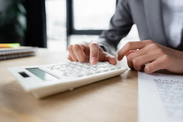 Cropped view of businesswoman using calculator near blurred paper — Stock Photo