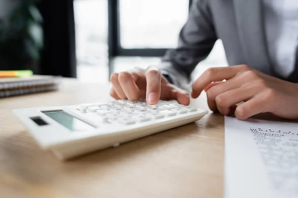 Vista recortada de la mujer de negocios utilizando la calculadora cerca de papel borroso - foto de stock