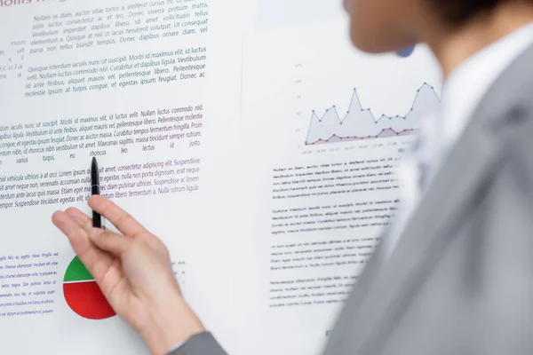 Ausgeschnittene Ansicht eines Kugelschreibers in der Hand einer afrikanisch-amerikanischen Geschäftsfrau in der Nähe von Flipchart auf unscharfem Vordergrund — Stockfoto