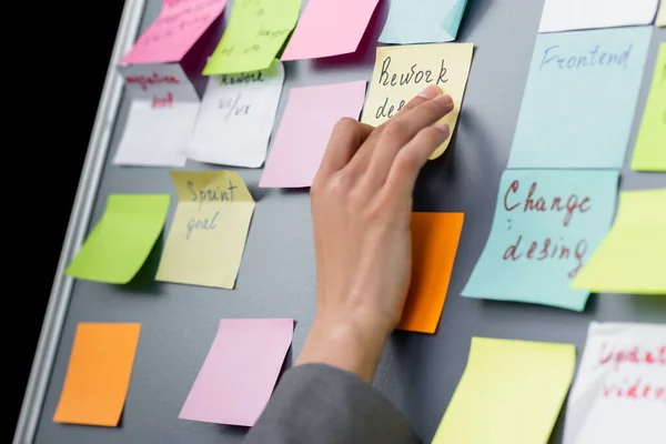 Vista recortada de la mujer de negocios aplicando nota adhesiva con letras a bordo - foto de stock