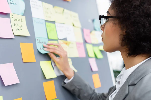 Young african american manager sticking blurred notes — Stock Photo