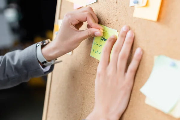 Cropped view of businesswoman attaching sticky note on board — Stock Photo