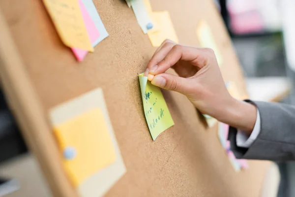 Cropped view of businesswoman attaching sticky note on board — Stock Photo