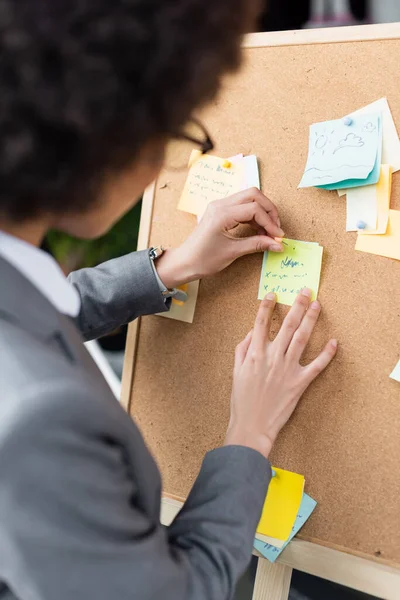 Empresaria afroamericana borrosa sosteniendo alfiler y notas adhesivas - foto de stock