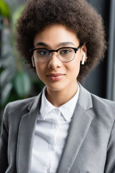 Mujer de negocios afroamericana en auriculares mirando a la cámara - foto de stock