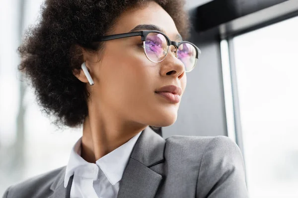 Femme d'affaires afro-américaine écoutant de la musique dans un écouteur — Photo de stock