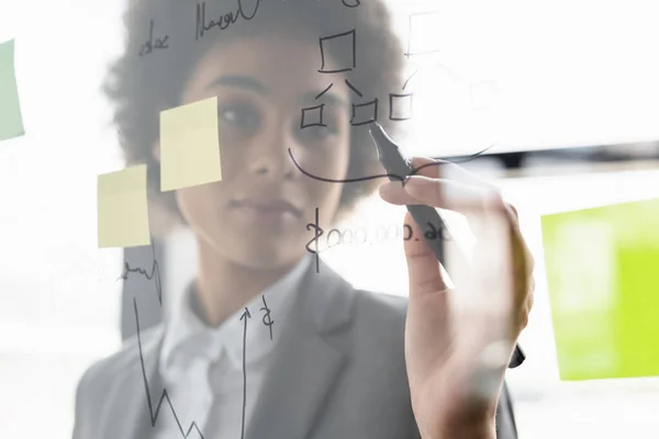 Blurred african american businesswoman writing on glass board — Stock Photo
