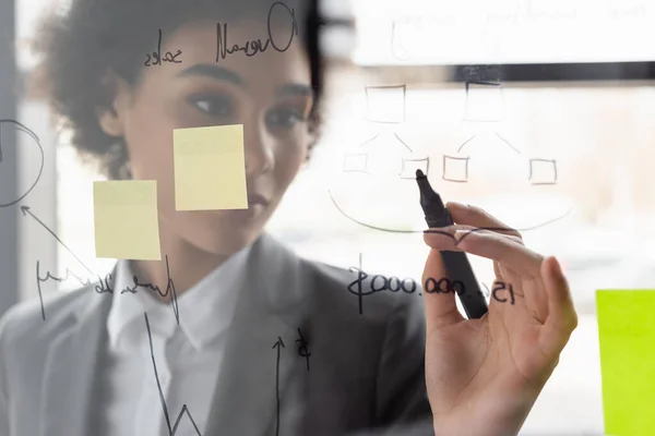 African american businesswoman drawing on glass board in office — Stock Photo
